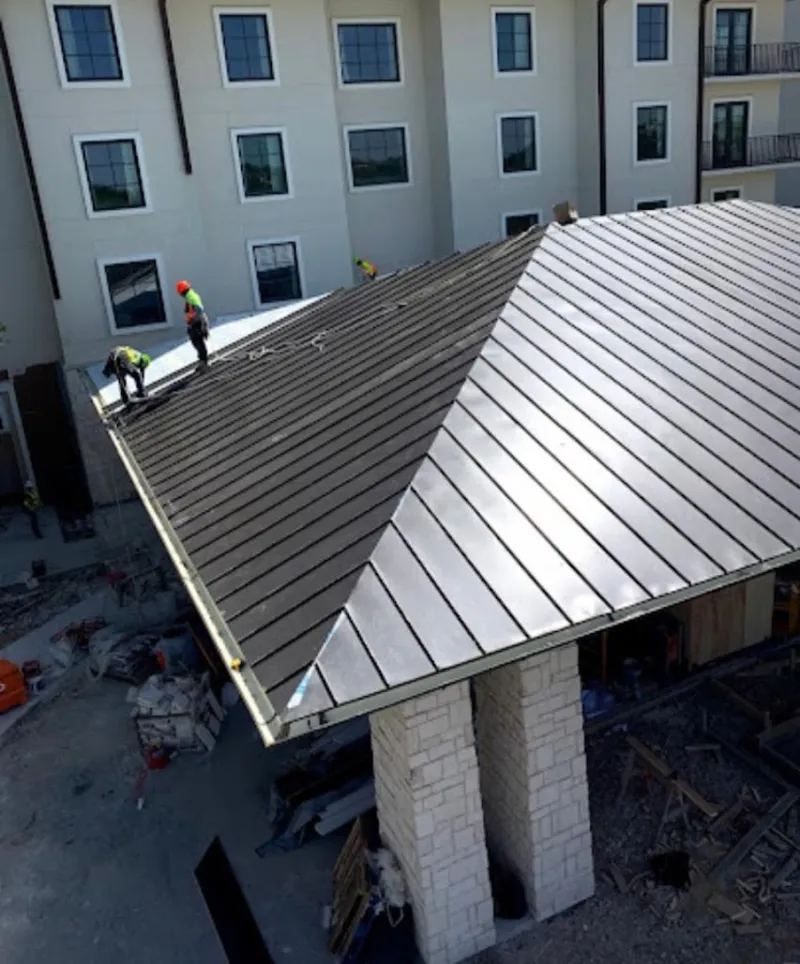 Crew installing standing seam metal roof panels on a commercial project in Festus
